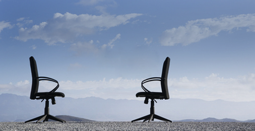 Two empty office chairs on top of a mountain