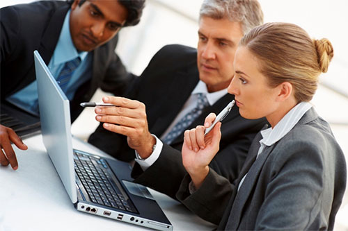 Business People Gathered Around Laptop